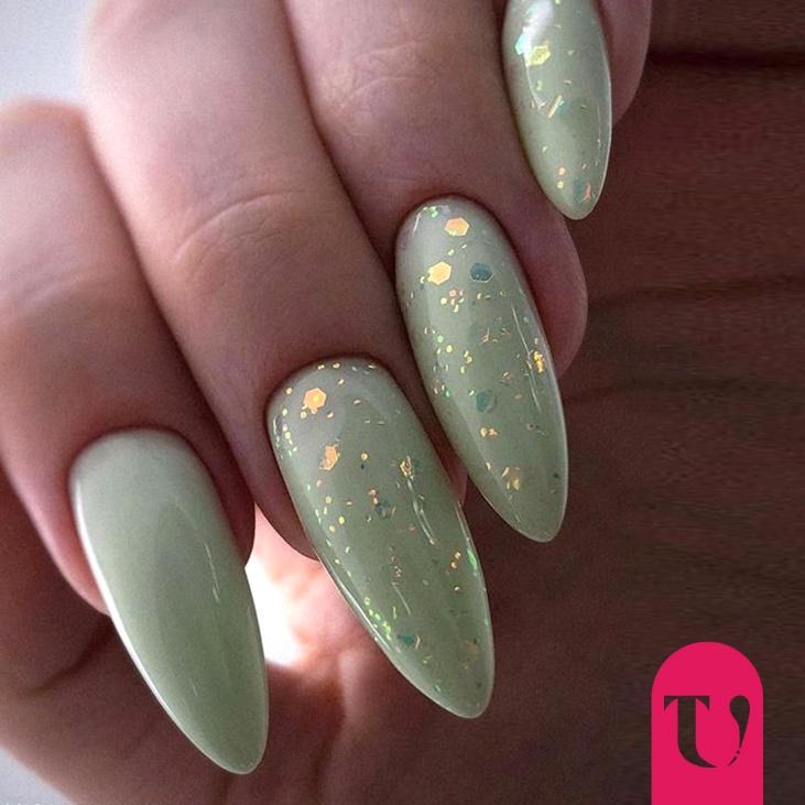 Smalto color verde salvia con glitter su unghie a mandorla